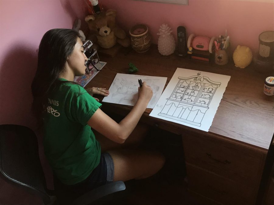 Senior Lauren Rodriguez concentrating on drawing flowers in a room scene while listening to music.