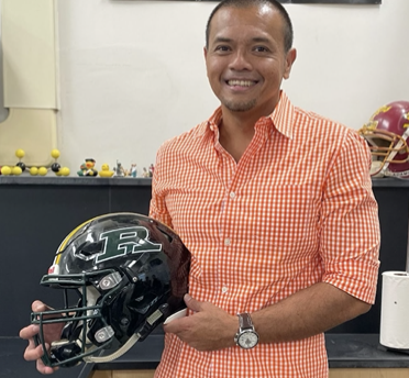 Winner of the campus poll of Favorite RHS Teacher, Mr.Acab holding his football helmet 