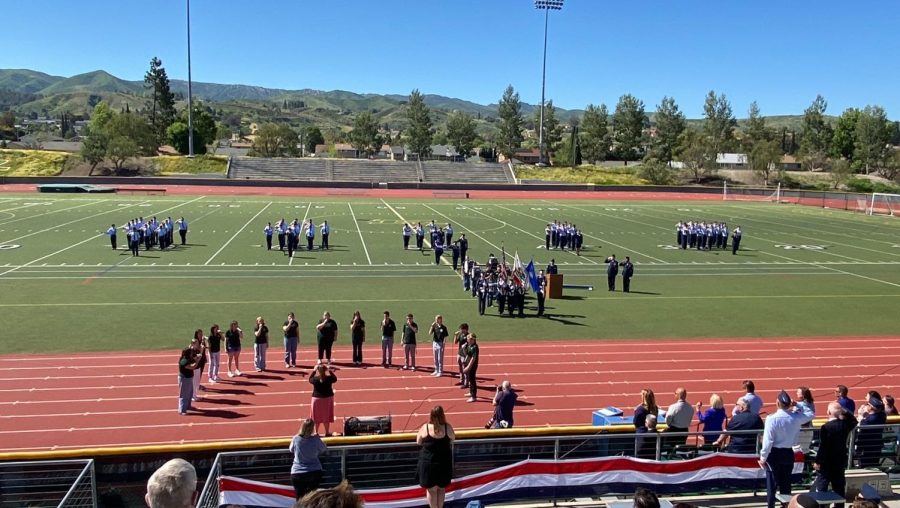 AFJROTC+saluting+to+the+national+anthem+sung+by+Highland+Harmonics%2C+as+well+as+audience+members+standing+with+respect.+