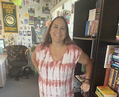 English Teacher Mrs. Setmire stocking a bookshelf before class, wearing a signature flowy dress.