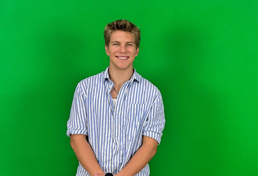 Senior Luke Lacy, standing in front of the green screen, ready to broadcast the video announcements. 