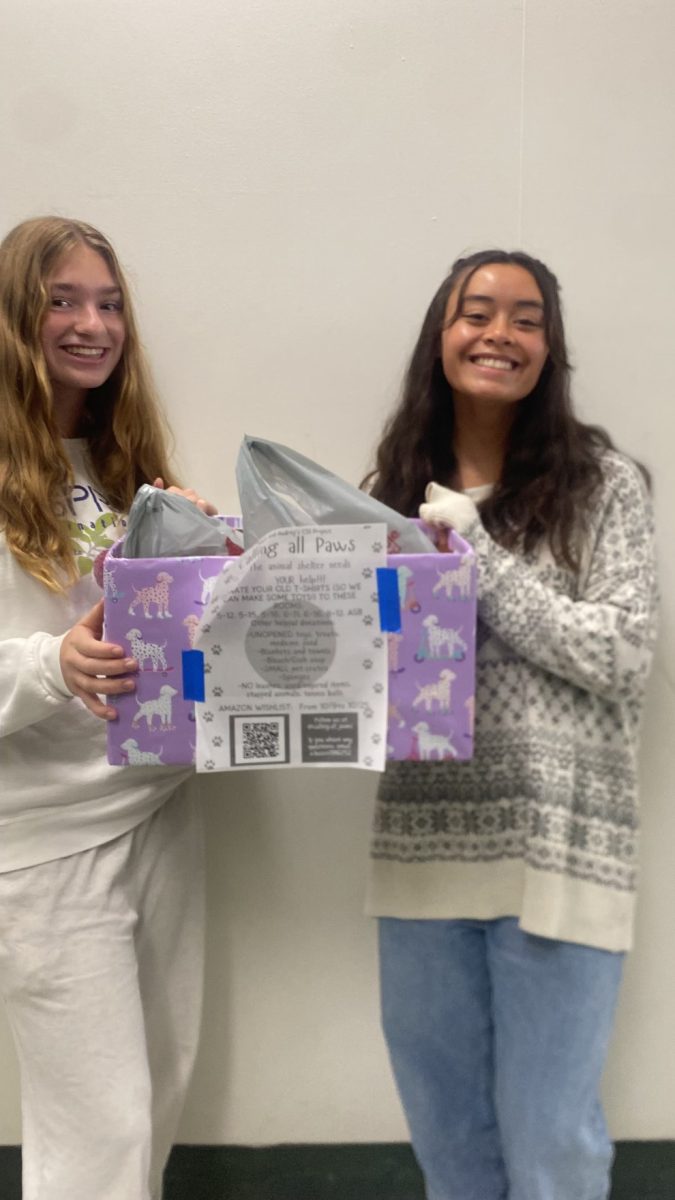 Sophomores Angela Busco and Audrey Pulsipher collecting a box of donations from one of the classes.