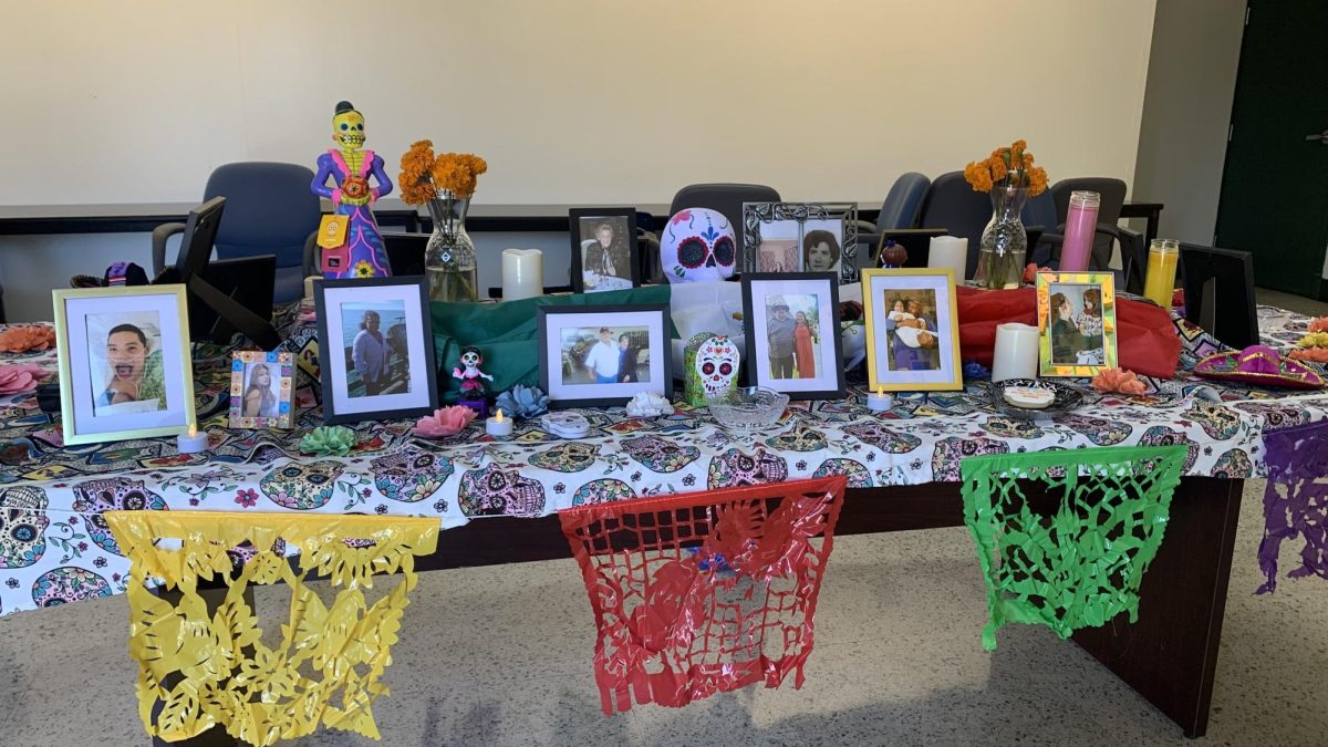 An ofrenda filled with memories: photos, marigolds, candles, and colorful papel picado honor the lives of loved ones, inviting their spirits back for Día de los Muertos.