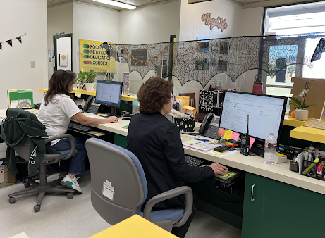 Ms. Rita Zepeda and Ms. Jennifer Meyer Barr working in their desks surrounded by decorations for Halloween.