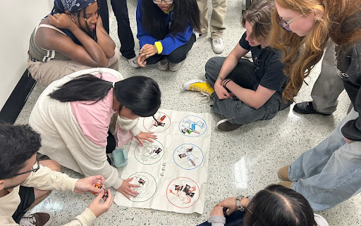 SEACC members participate in a game of Bầu cua cá cọp during the Southeast Asian Cultural Club's Lunar New Year celebration. The game, a Vietnamese tradition, involved students rolling animal-themed dice and working together in a circle on the floor.