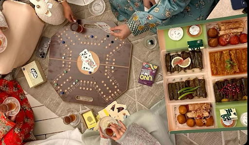 Friends and family gathered in a circle after Iftar, enjoying a fun game of UNO with delicious food on the side, sharing laughter and good times together.